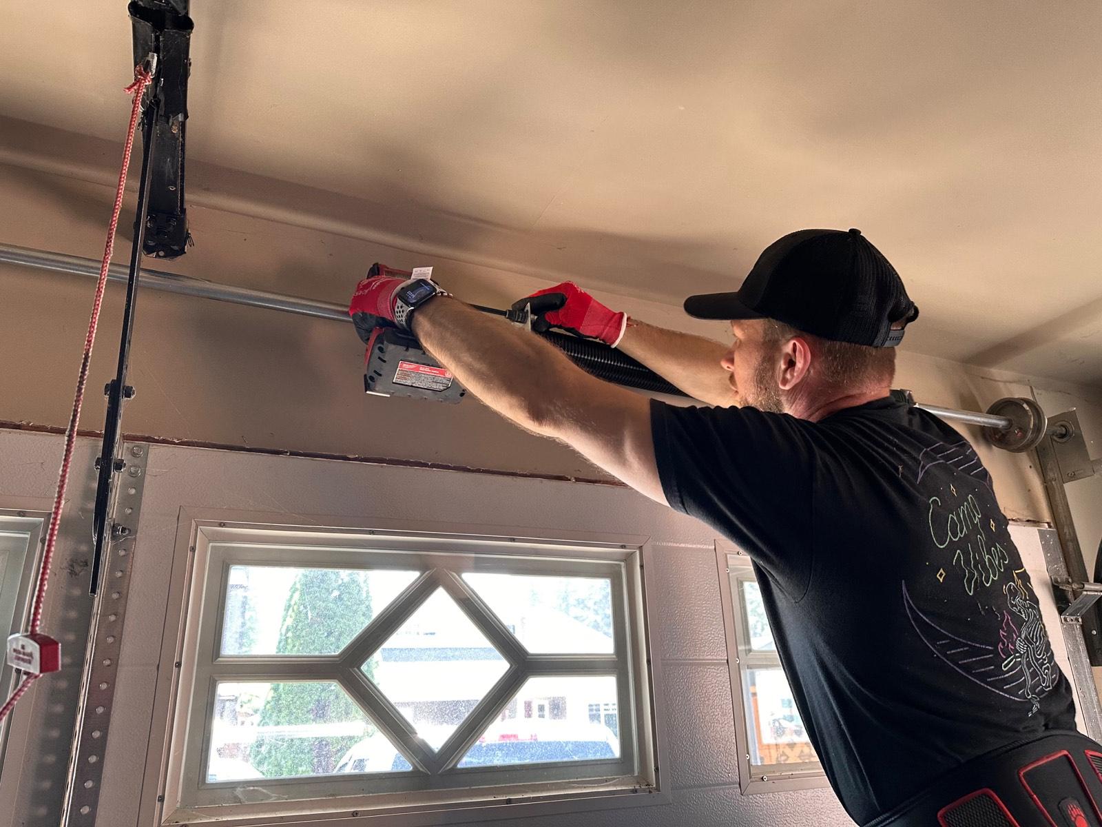 Technician fitting a new torsion spring above a garage door